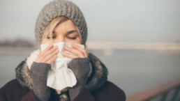 Woman blowing her nose outside