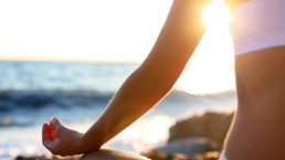 Woman meditating on the beach