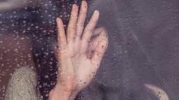 Sad woman looking outside window in the rain